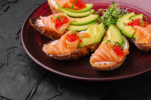 Salmon crostini with cream cheese, avocado, and salmon ikura.